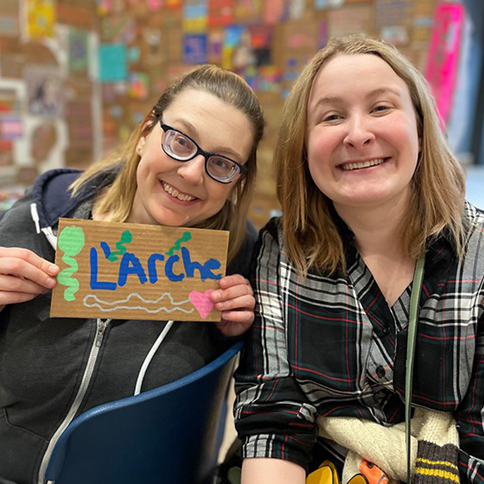 Two women smiling and holding a sign that says